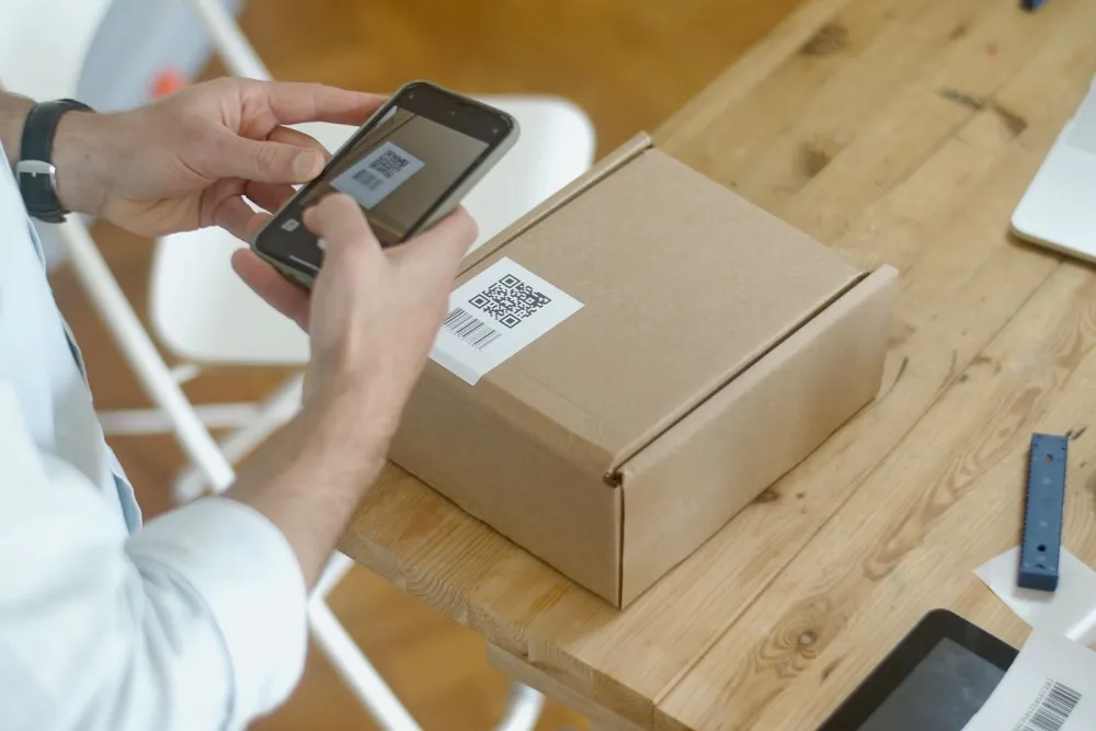A product carton with a printed QR code being scanned by a phone
